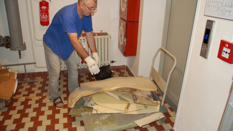Pracovník Domu s pečovatelskou službou odváží vodou zničené linoleum
