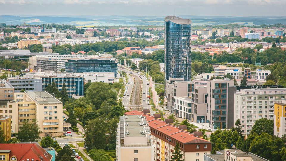 Skleněná budova mrakodrapu BEA Olomouc při pohledu z jiného olomouckého mrakodrapu RCO u vlakového nádraží. Uprostřed Třída Kosmonautů a vlevo vzadu obchodní centrum Galerie Šantovka