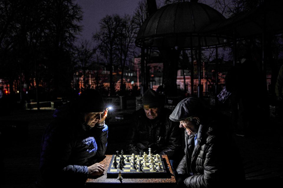 Muži v kyjevském parku hrají šachy,  svítit si musí baterkou. Kvůli ruskému jsou v celé zemi výpadky elektrického proudu. | foto: Sergei Chuzavkov / SOPA Images/S,  Reuters